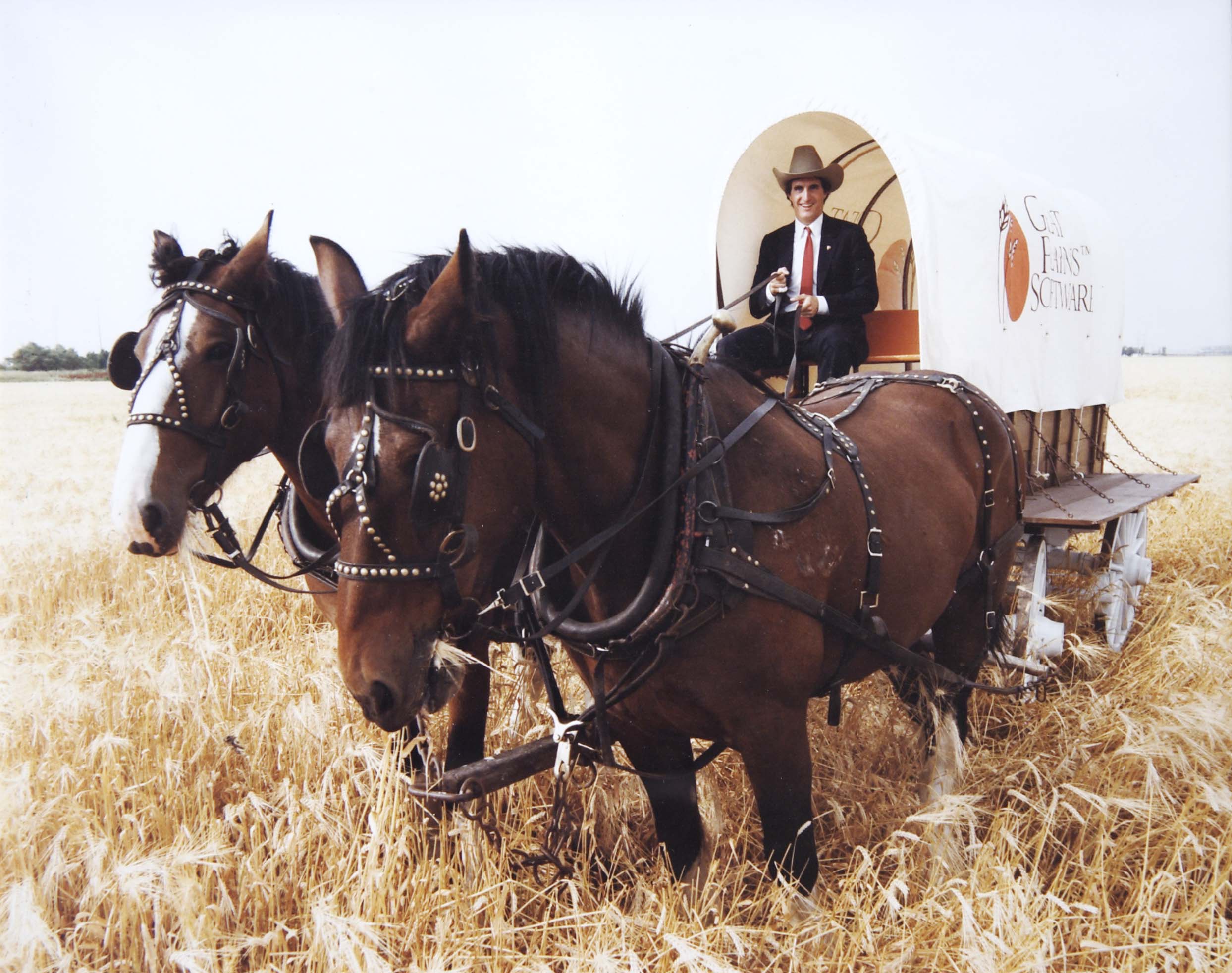 Doug Burgum seated on a covered wagon behind two horses 