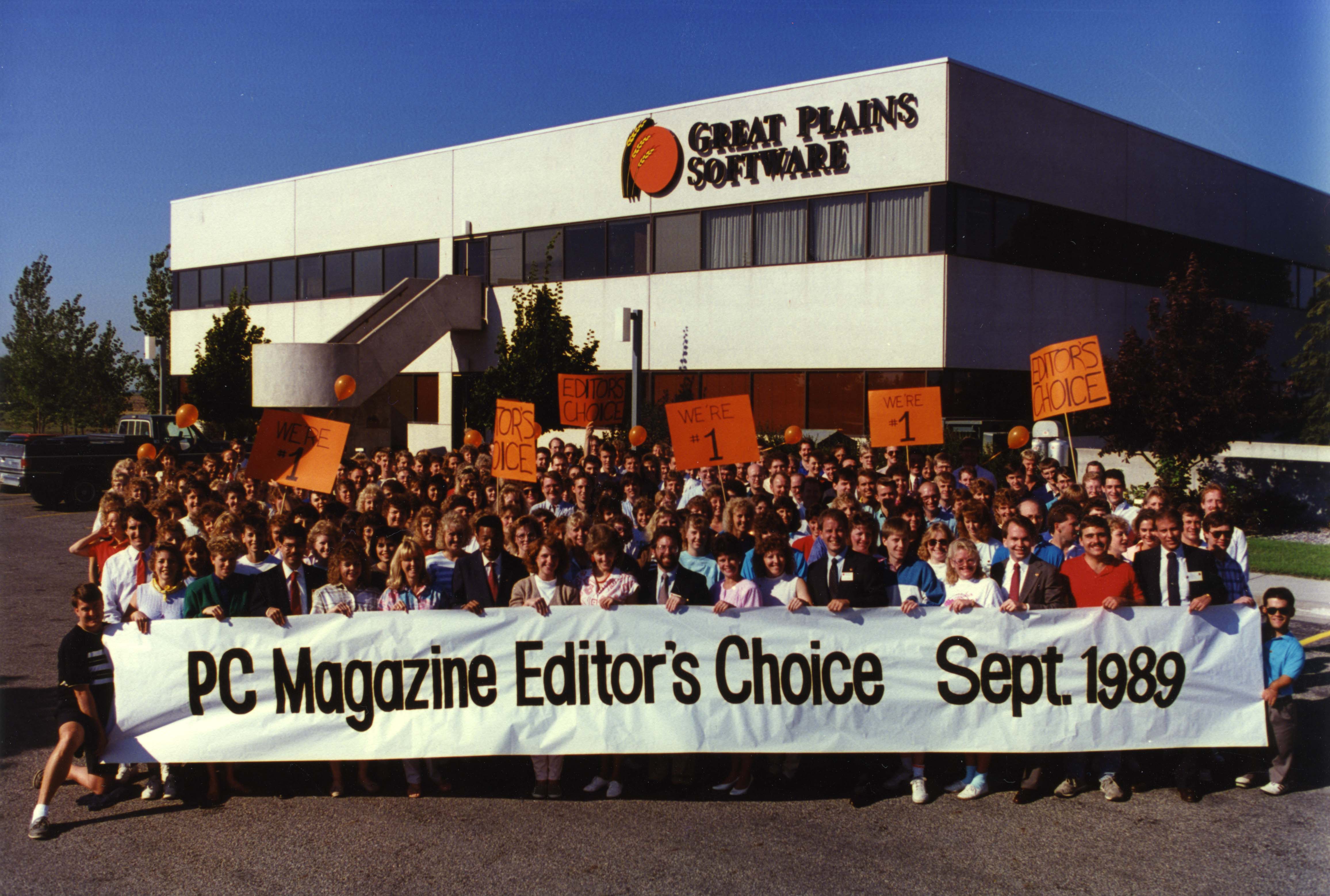 A group of people in front of the Great Plains Software building holding a banner that says "PC Magazine Editor's Choice Sept. 1989" 
