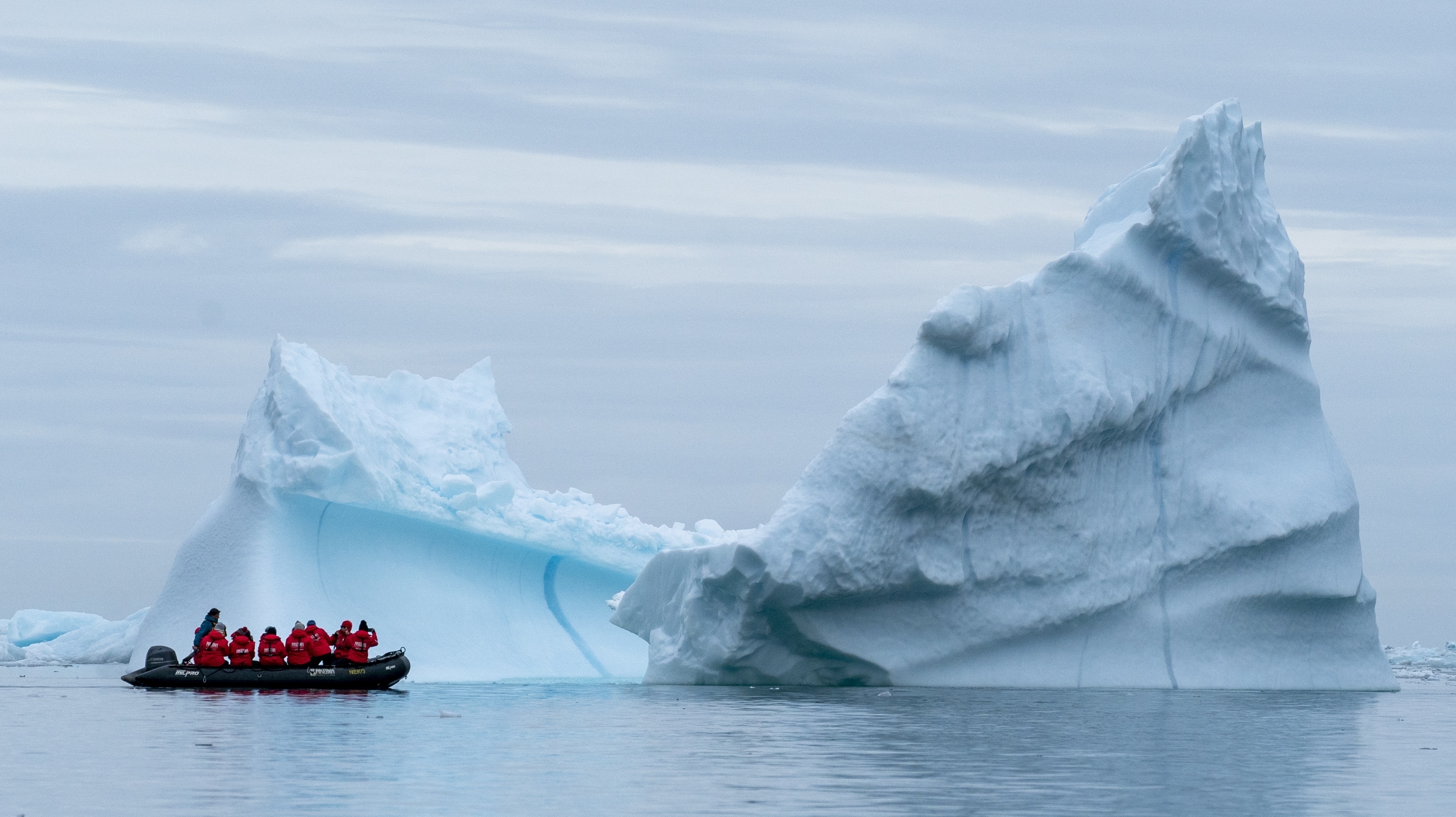 A group of travelers examine an iceberg in the Scoresby Sund of Greenland.