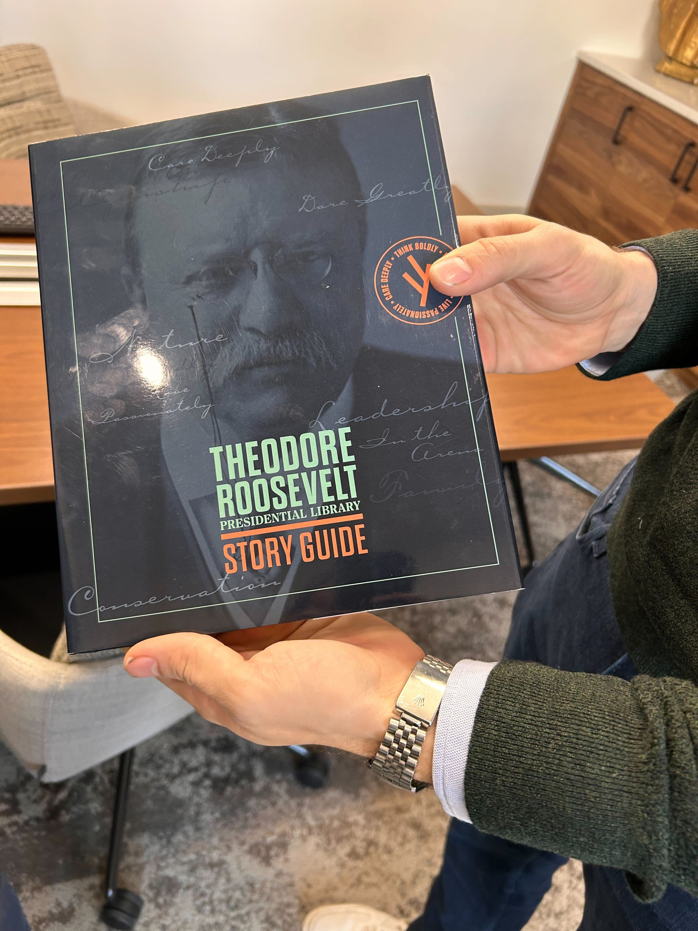 A person holds a story guide for the Theodore Roosevelt Presidential Library.