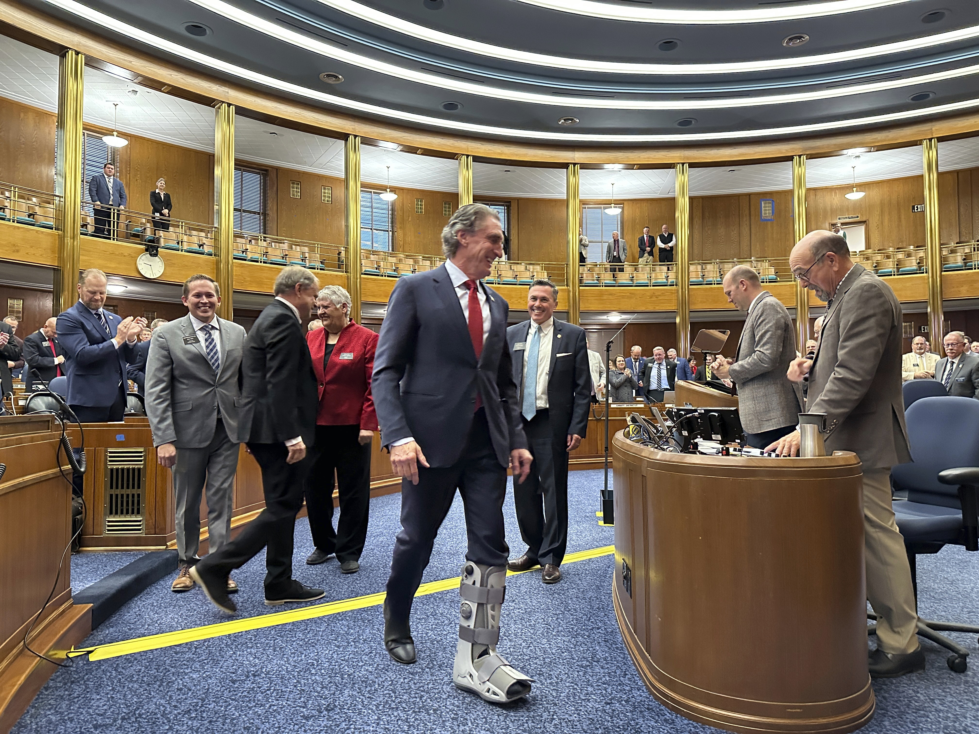 North Dakota Republican Gov. Doug Burgum (center) walks to the rostrum in the state House of Representatives.